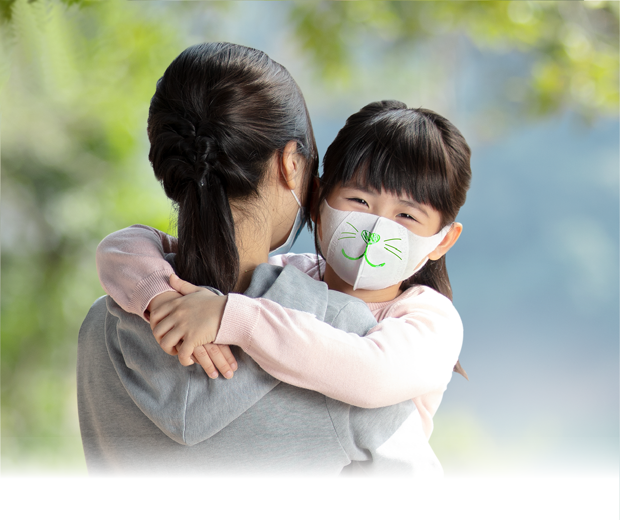 A mother holds her masked daughter in the countryside
